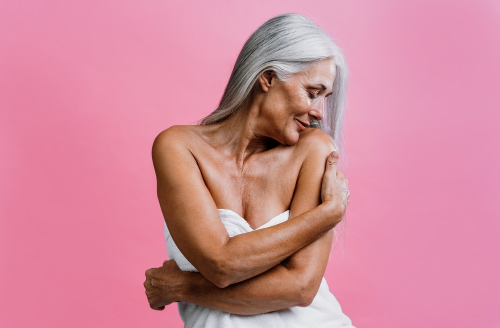 Mulher de idade abraçando próprio corpo.