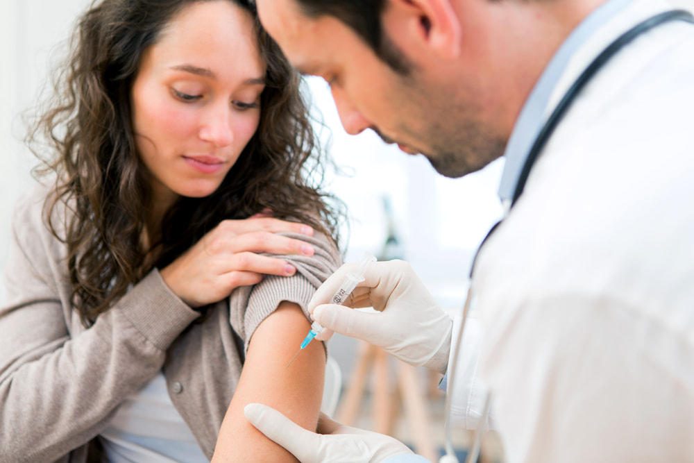 Médico aplicando injeção em paciente mulher.