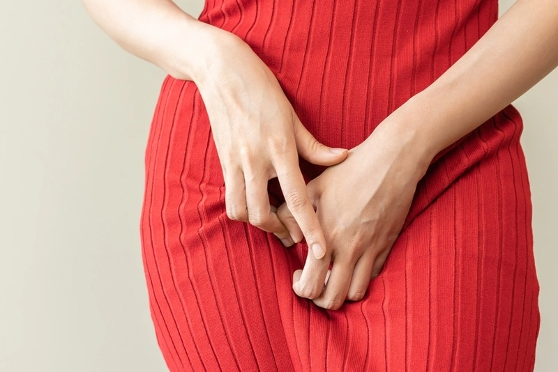 Mulher com mãos nas partes íntimas sentindo desconforto